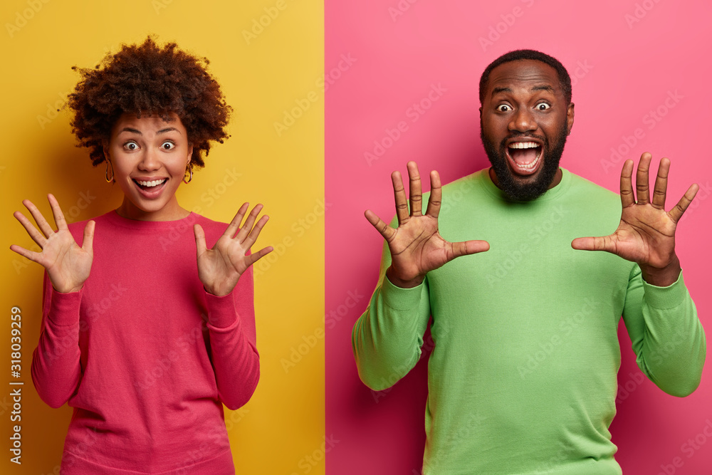 Φωτογραφία Indoor shot of overjoyed overemotive ethnic woman and man raise palms, stare emo