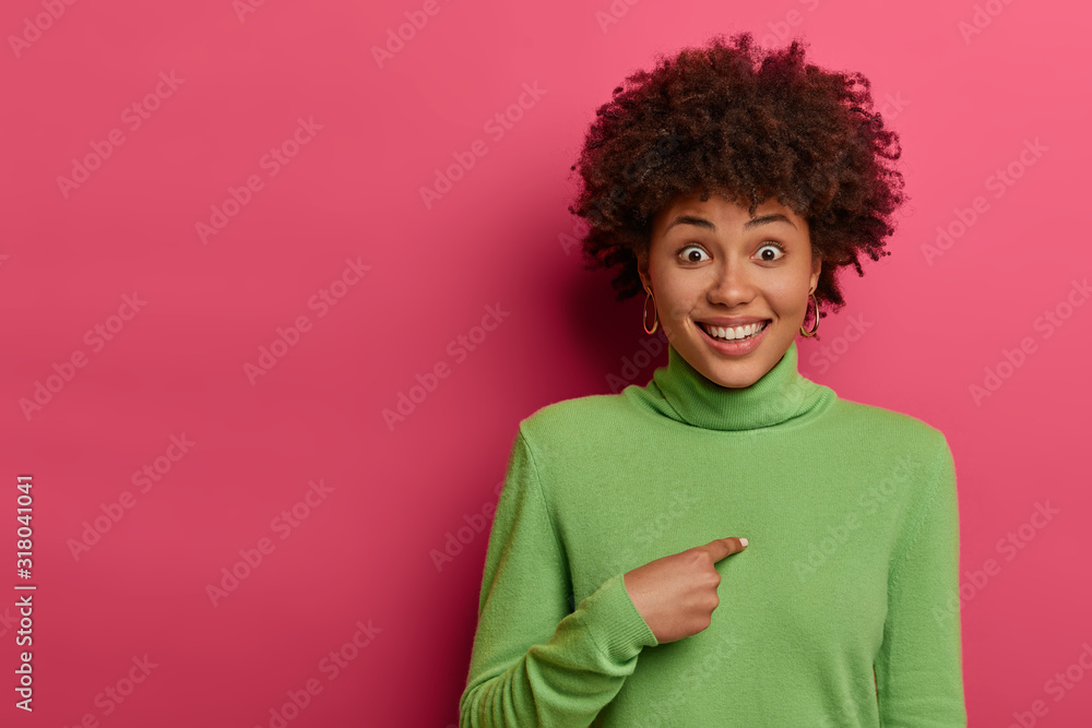 Who me? Joyful woman points at herself and smiles, being chosen or promoted, cant believe her luck and picked, feels uplifted and happy, wears green turtleneck, poses against pink background Who me? Joyful woman points at herself and smiles, being chosen or promoted, cant believe her luck and picked, feels uplifted and happy, wears green turtleneck, poses against pink background