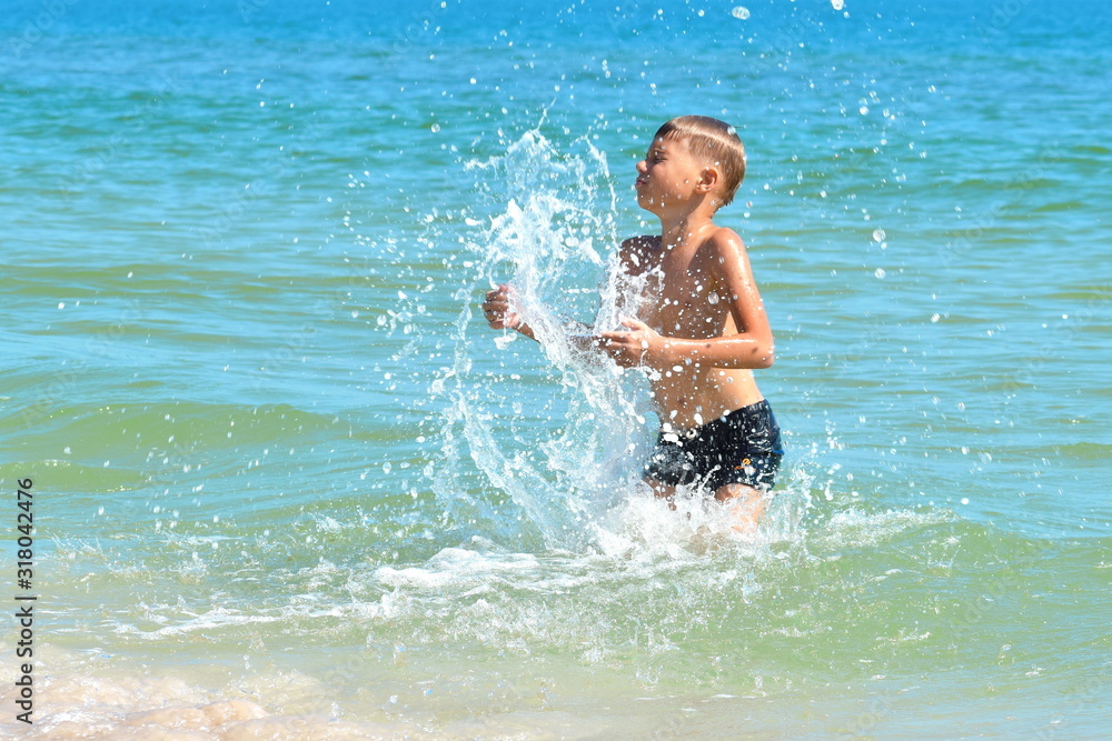 A little boy playing in the sea water. A child jumps from the sea. A tropical vacation with children.