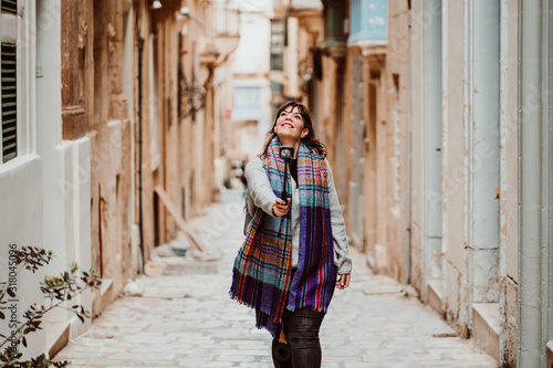 .Young female tourist touring Valletta, capital of Malta. Travelling with a compact camera to broadcast her trip on social networks. Lifestyle