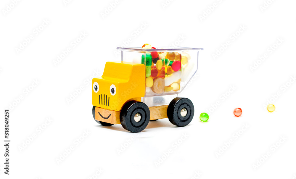 Truck car toy delivers vitamins pills medications for baby child on a white isolated background. Truck car toy delivers vitamins pills medications for baby child on a white isolated background.