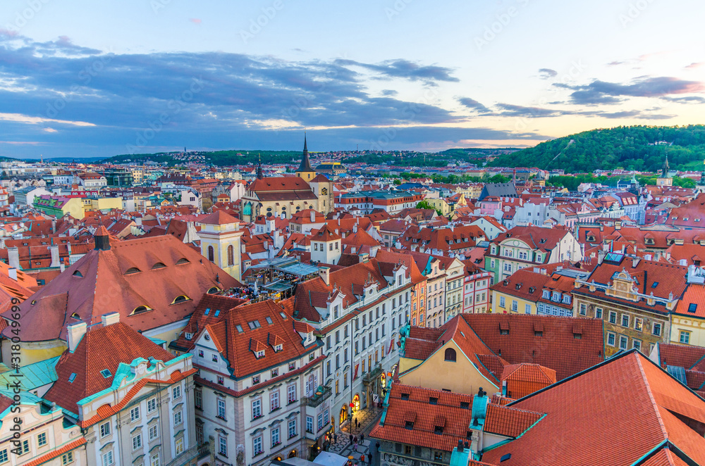 Top aerial panoramic view of Prague Old Town (Stare Mesto) historical city centre with red tiled roof buildings and Petrin hill garden in evening sunset, Bohemia, Czech Republic