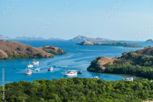 A view from top of the Komodo Island in Indonesia. Discovering new places. There is a lot of boats anchored to the shores of the island's bay. Other islands in the back. Volcanic island.
