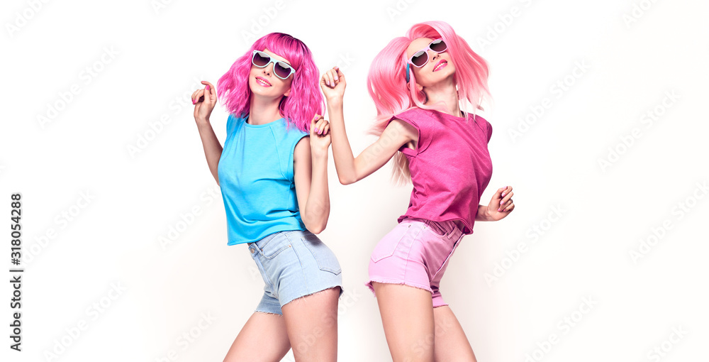 Two Young carefree Woman with stylish pink hair, in shorts jump dance. Beautiful fashionable model girl in colorful summer outfit. Joyful friends with fashion pink hairstyle dancing on white, banner Two Young carefree Woman with stylish pink hair, in shorts jump dance. Beautiful fashionable model girl in colorful summer outfit. Joyful friends with fashion pink hairstyle dancing on white, banner