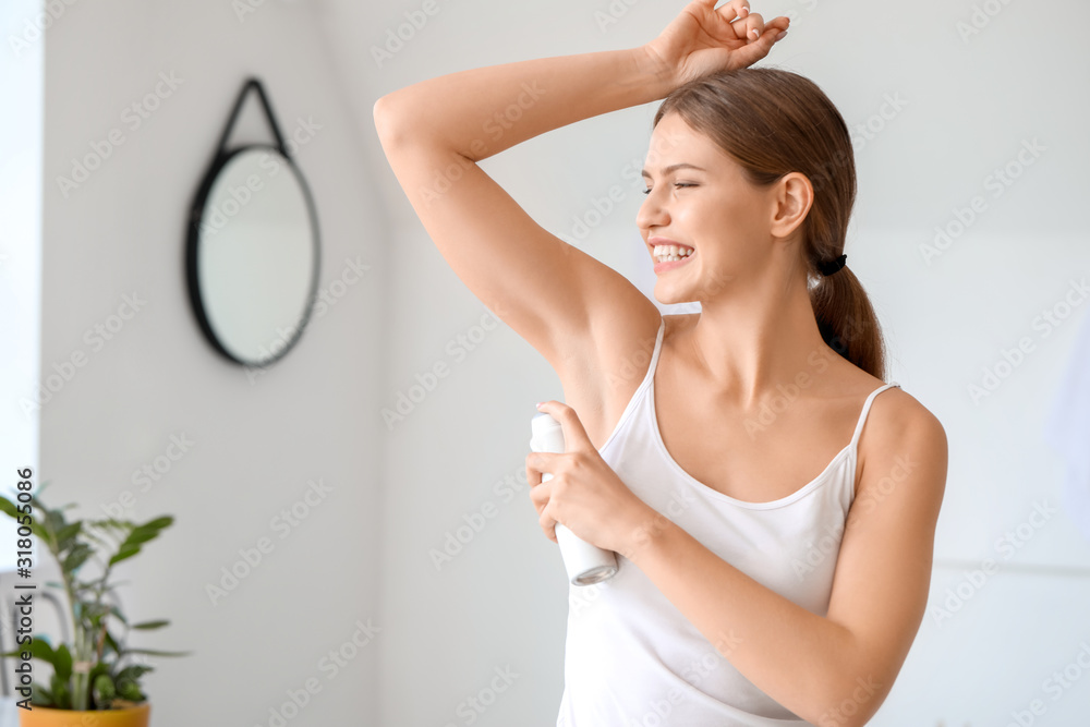 Beautiful young woman using deodorant at home Beautiful young woman using deodorant at home