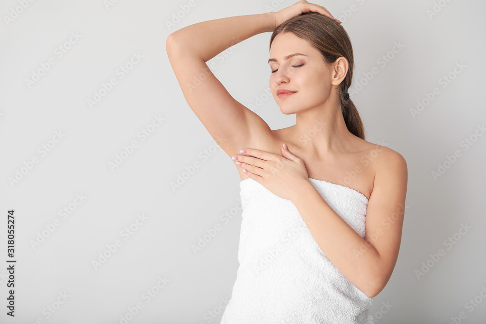 Beautiful young woman after shower on light background. Concept of using deodorant Beautiful young woman after shower on light background. Concept of using deodorant