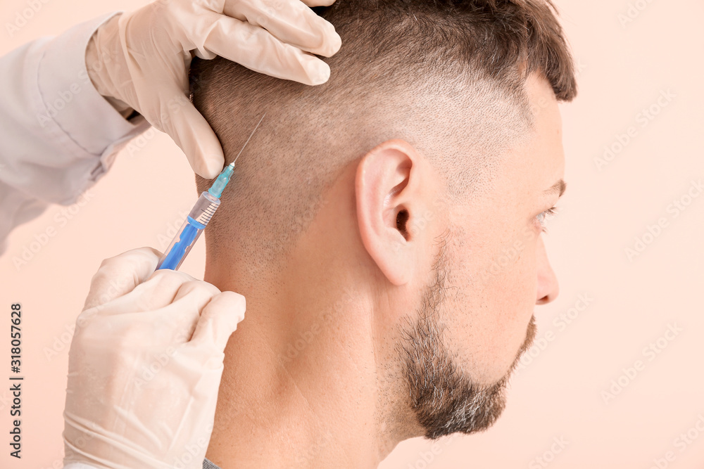 Man with hair loss problem receiving injection on color background