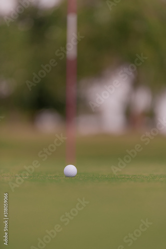 Golf ball sitting close to the hole