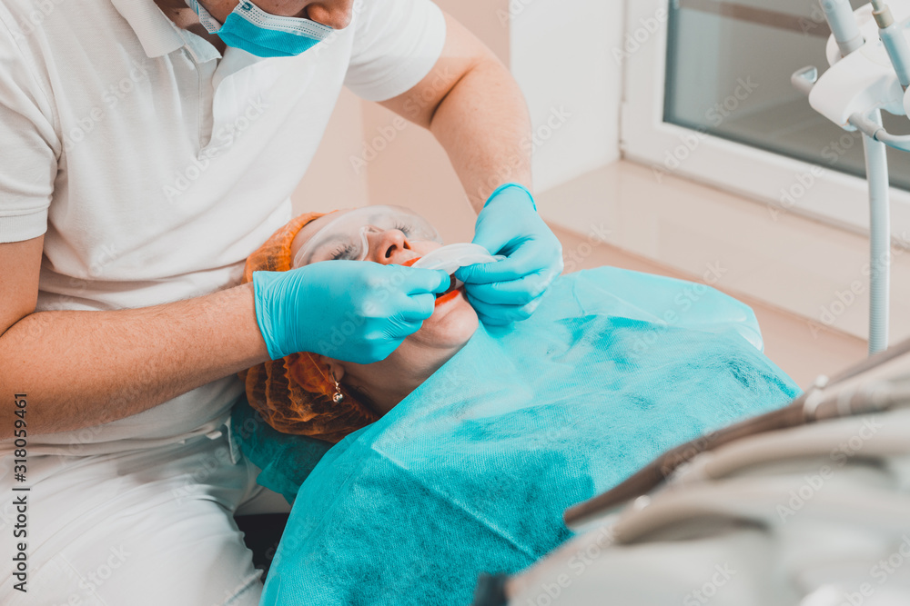 A young female dentist pulls a mouth extender at a dental clinic. A young female dentist pulls a mouth extender at a dental clinic.