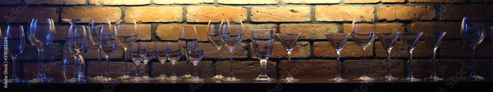 Naklejka premium Glasses against the backdrop of an illuminated brick wall
