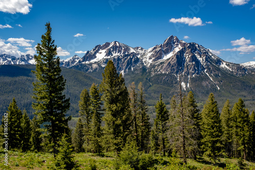 Green forest blankets the base of a high peak in the Sawtooths of Idaho