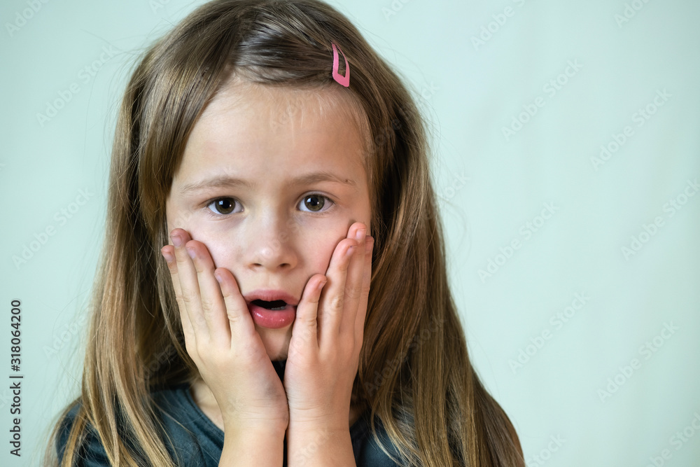 Close-up portrait of little child girl with long hair covering her mouth with hands. Close-up portrait of little child girl with long hair covering her mouth with hands.