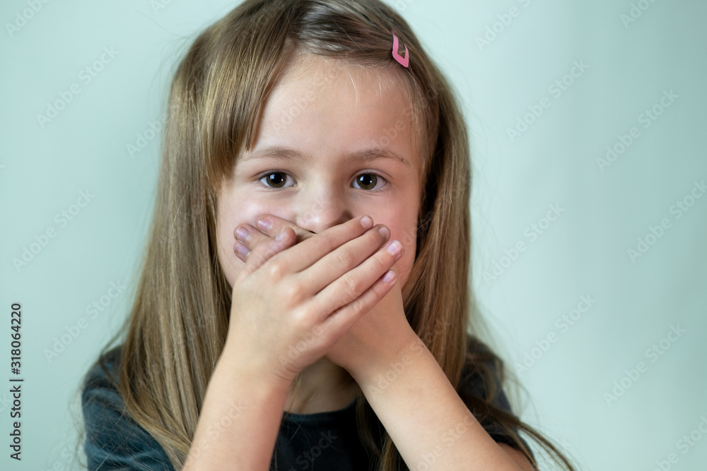 Close-up portrait of little child girl with long hair covering her mouth with hands. Close-up portrait of little child girl with long hair covering her mouth with hands.