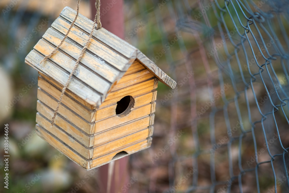 Small wooden bird house hanging on a tree branch outdoors. Small wooden bird house hanging on a tree branch outdoors.