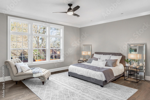 Beautiful bedroom in new luxury home with large windows and area rug photo