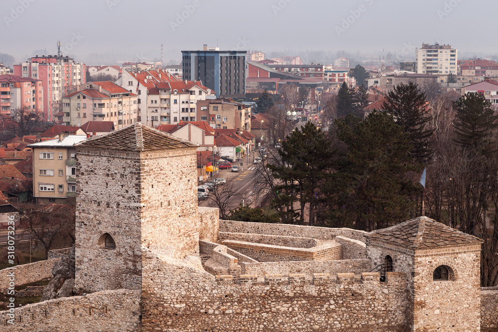 Beautiful panorama of Pirot cityscape, with foreground ancient fortress Momcilov grad and city buildings and houses in the background during cloudy, cold winter day