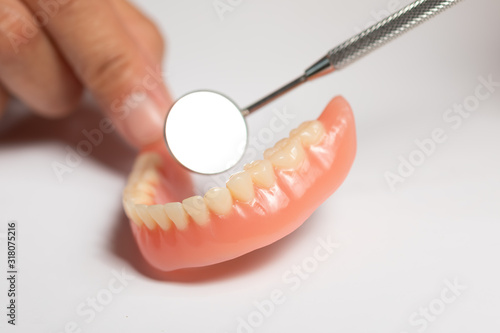 Denture prosthesis in doctor orthodontist dentist hand, checking with mirror