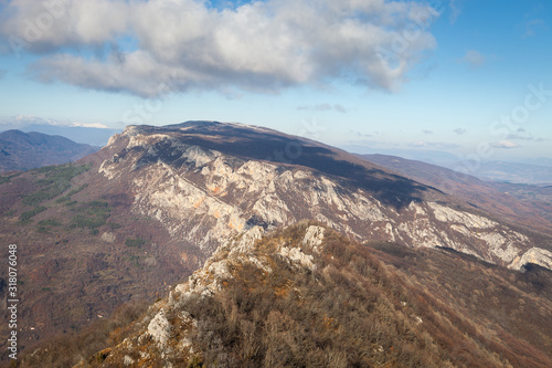 Beautiful rocky mountain peak, forests colored with late autumn colors and blue sky with soft clouds over Vlaska planina in Serbia, near village Vlasi photo