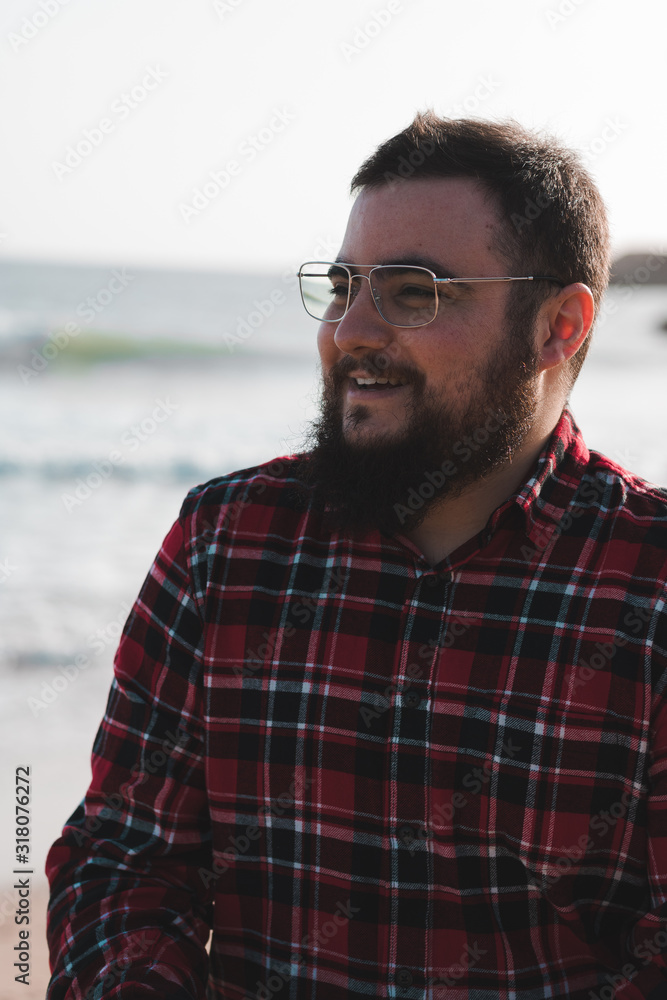 portrait of smiling young man with red shirt, beard and glasses portrait of smiling young man with red shirt, beard and glasses