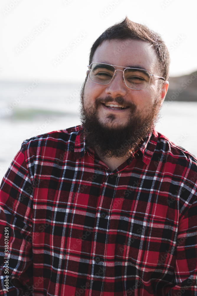 portrait of smiling young man with red shirt, beard and glasses portrait of smiling young man with red shirt, beard and glasses