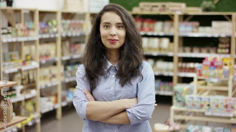 Portrait of young beautiful caucasian woman smiling slightly, looking at camera, folding her arms on her chest, in supermarket background. Portrait of young beautiful caucasian woman smiling slightly, looking at camera, folding her arms on her chest, in supermarket background.