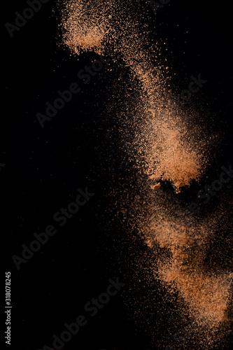 Cocoa powder explosion in motion on black background. Chocolate dust.