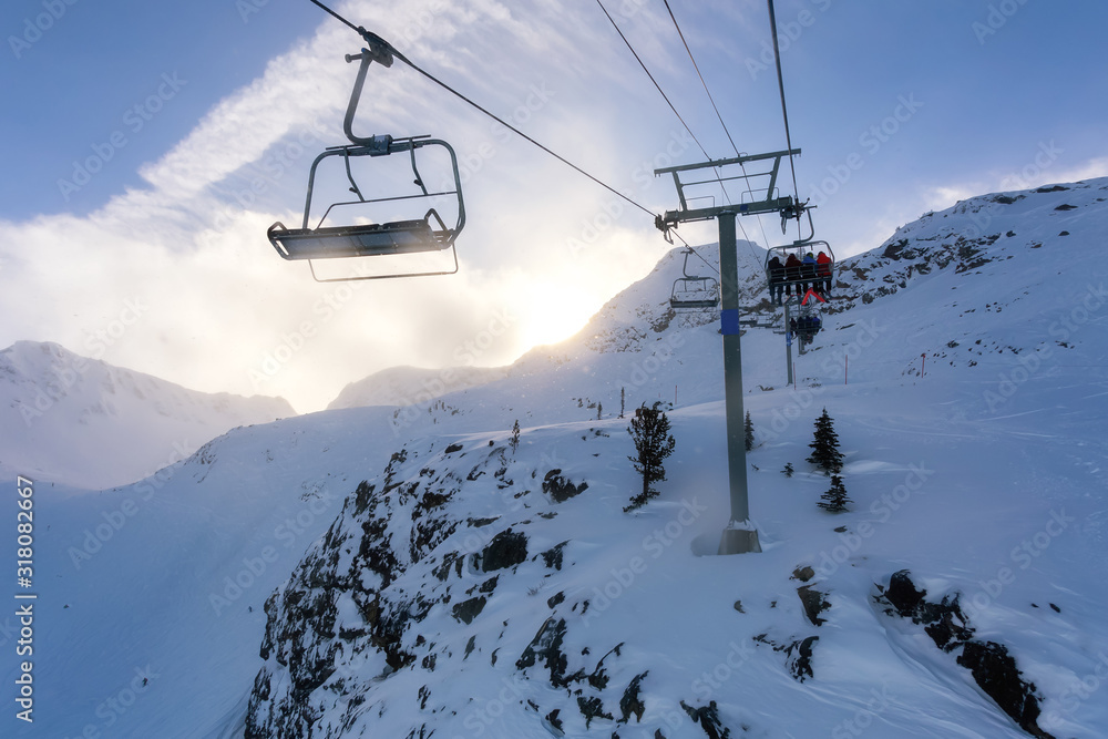 Fototapeta premium Whistler Ski Resort, British Columbia, Canada. Beautiful View of the snowy Canadian Nature Landscape Mountain and Chairlift going to the peak during a vibrant winter morning.