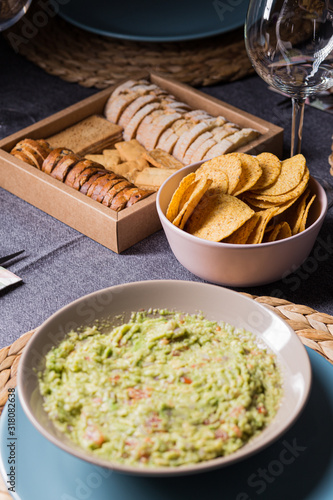 Green guacamole Mexican sauce food on a plate with bread toast slices close up still no a dark dinning table photo