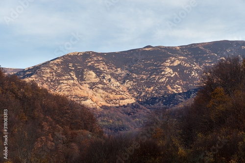Burnt mountain highlands turned in to dust after a fire, colorful autumn colored trees and soft, blue sky