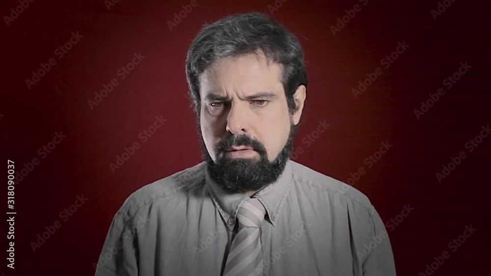 An alienated man's expression. Medium close-up shot of the face over a red background. Part of a series of depictions of feelings and emotions with professional actors. An alienated man's expression. Medium close-up shot of the face over a red background. Part of a series of depictions of feelings and emotions with professional actors.