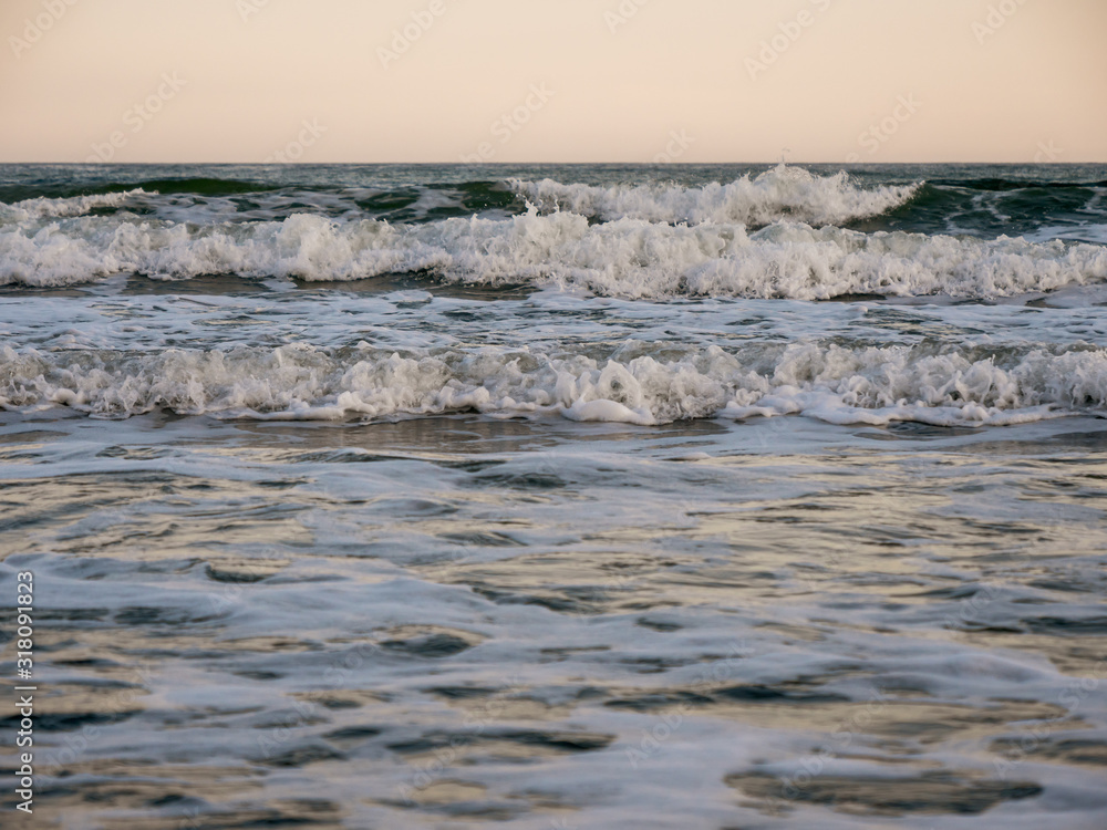 Waves of the sea foam near the coast. Dawn.