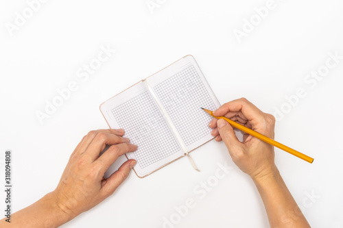 Woman hands holding a notebook and a yellow pencil and writing  close up top view copy space