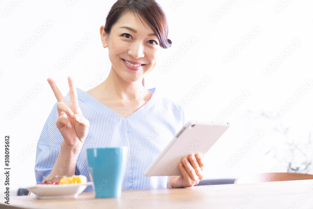 部屋でタブレットコンピューターを見る女性