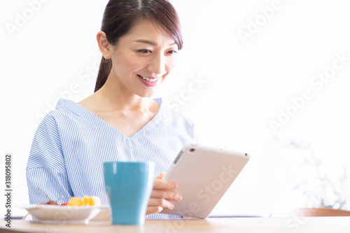 部屋でタブレットコンピューターを見る女性