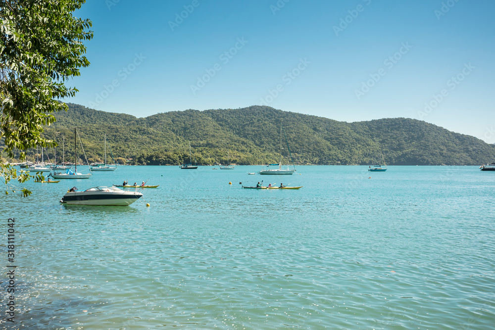 Blue and green beach vacation in the village of Abraao with boats on a sunny day, on the tropical island Grande, Rio de Janeiro, Brazil, South America.