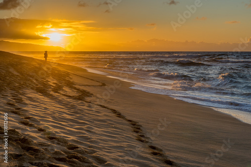 Fototapeta Naklejka Na Ścianę i Meble -  Silhouette of a woman walking on Sunset Beach on the north shore of Oahu, Hawaii at sunset