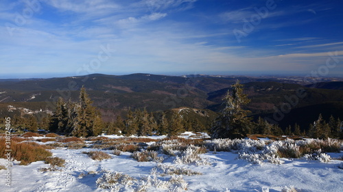 View on hilly snowless forests from snowy mountain on a sunny day