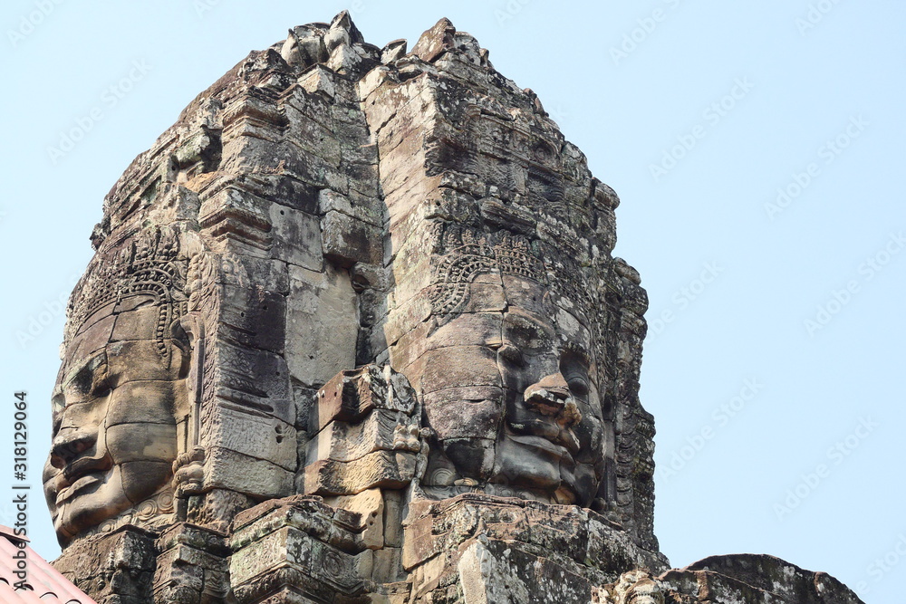Stone faces of God at Bayon Temple in Angkor Thom, One of the main attractions, Sculpture carved in ancient times with Hindu belief with blue sky in background at Siem Reap , Cambodia