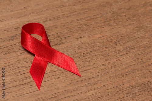 Red ribbon Aids awareness for World HIV/AIDS day on wooden background.