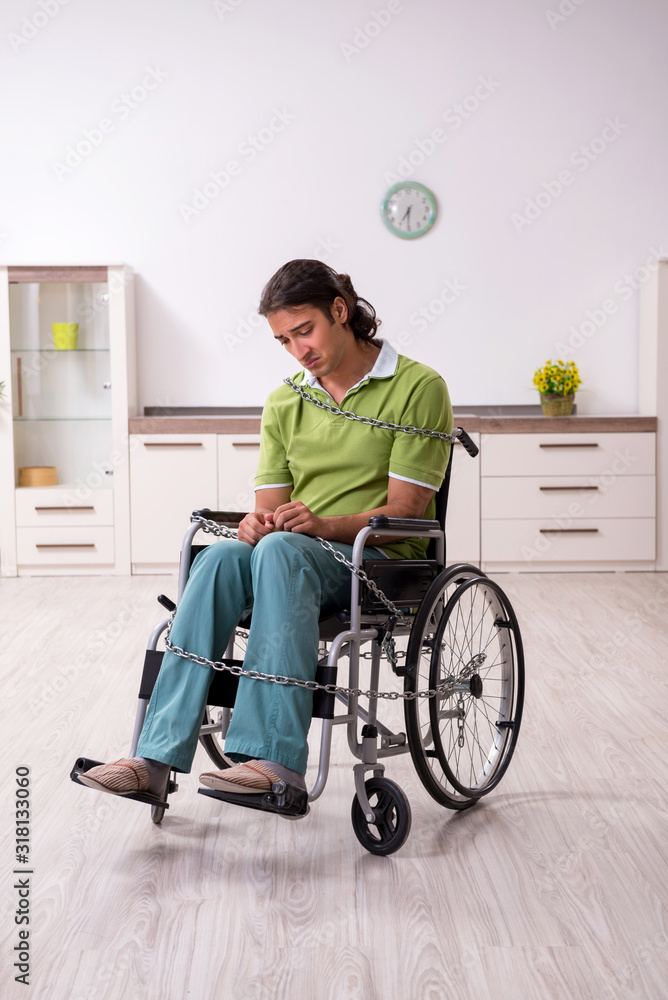 Young male invalid in wheel-chair suffering at home Young male invalid in wheel-chair suffering at home