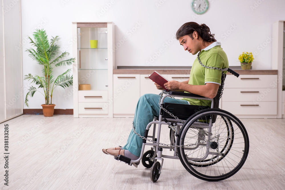 Young male invalid in wheel-chair suffering at home Young male invalid in wheel-chair suffering at home