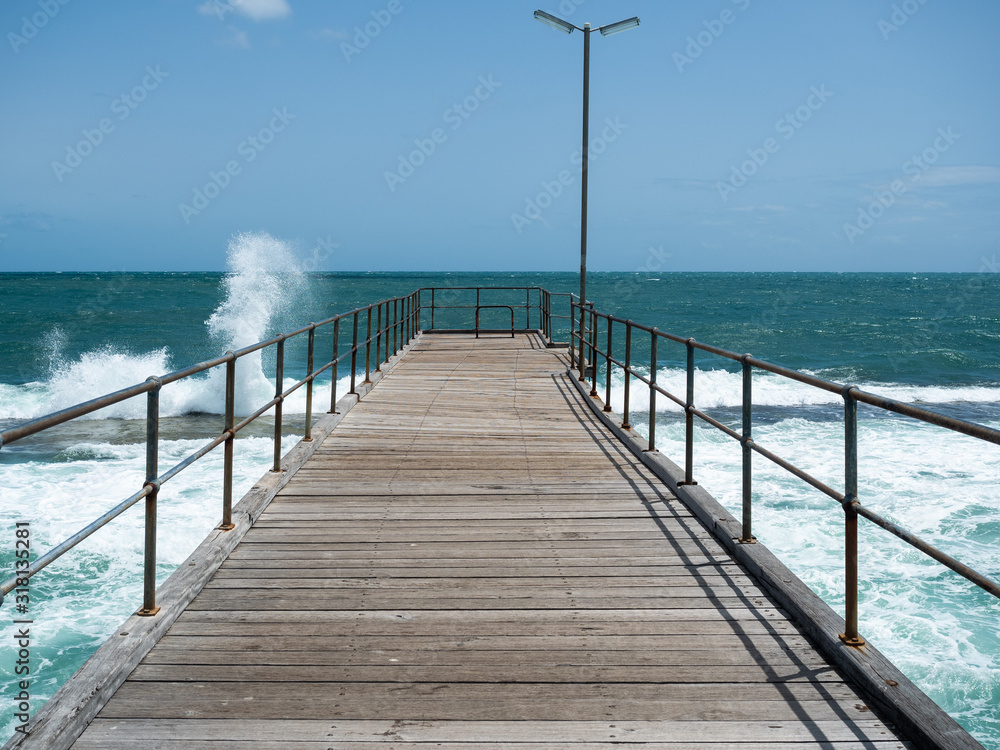 Rough seas smashing on the reef and The Port Noarlunga jetty in South Australia on 23rd January 2020