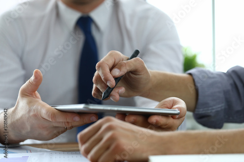 Close-up of workers discussing new start-up. Customer signing electronic document in office. Man pointing with stylus on laptop. Business company and innovation concept