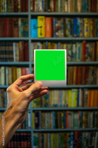 Holding Polaroid in front of bookshelf (portrait)