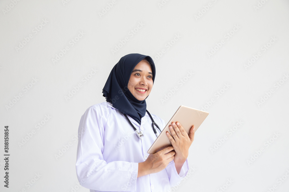 Young Asian Muslim woman hijab doctor or nurse in white uniform scrubs holding a tablet pc standing in front of a Young Asian Muslim woman hijab doctor or nurse in white uniform scrubs holding a tablet pc standing in front of a