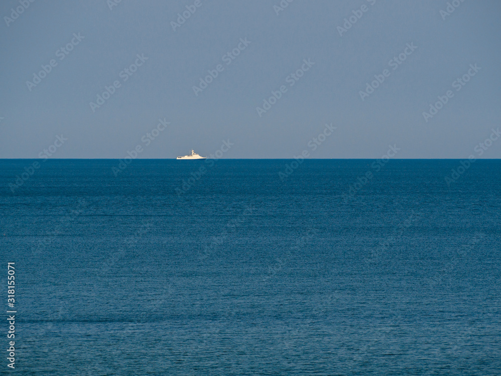 Warship of coast guard on the horizon, patrolling in a calm sea. Baltic sea