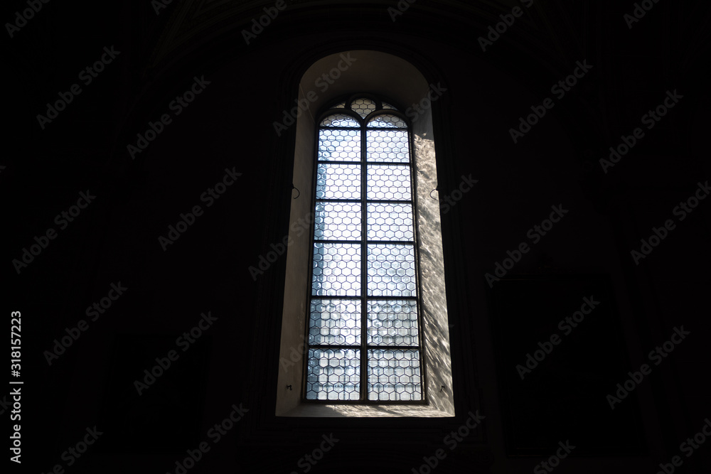 Front view of light through a Gothic stone church window among the dark background , copy space , wallpaper