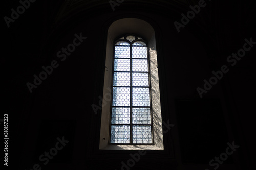 Front view of light through a Gothic stone church window among the dark background   copy space   wallpaper
