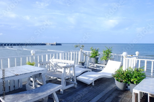 Seascape view of beach facing out to the ocean. White beach chairs and blue sky with some cloud in the background. Vacation and holiday on beach concept.