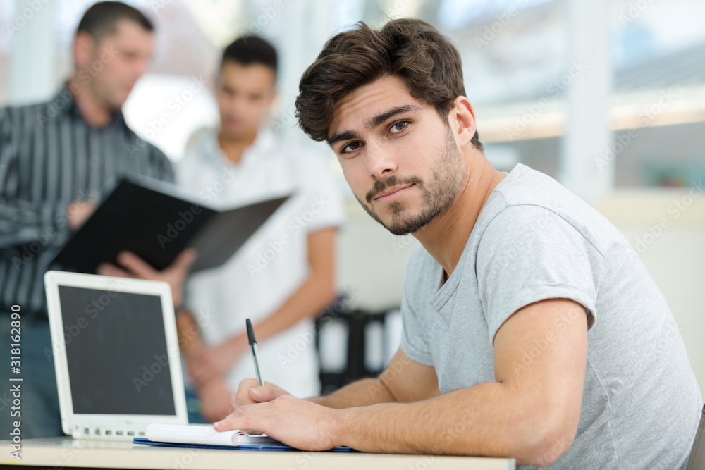 portrait of young man at desk with notebook and pen portrait of young man at desk with notebook and pen